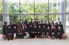 Graduation photo of Master's Class of 2023, sitting in a group wearing caps and gowns