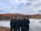 group of four people in front of a lake