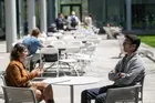 Two students sitting at an outdoor table and talking