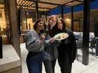 A group of students smiling on a patio and holding a plate of food