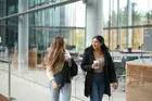 Two students holding coffees and walking through Evans Hall.