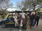 A group of people posing next to a safari vehicle