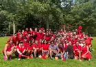 A group of people wearing red athletic apparel posing in an outdoor field