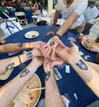 A photo showing several people with temporary tattoos of the Yale SOM logo on their wrists