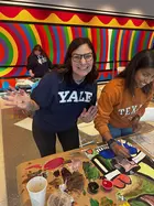 A person wearing a Yale sweatshirt participating in a finger-painting activity, with a colorful mural in the background