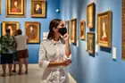 Woman in mask admiring museum artwork