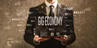 man in suit holding up a sign that says gig economy 