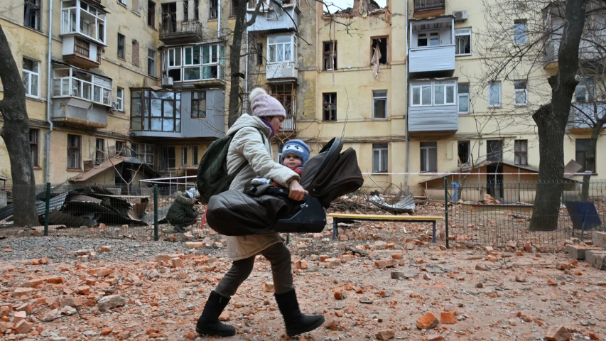 A local resident carries her baby outside of their residential building partially destroyed after a missile strike in Kharkiv on Jan. 30.