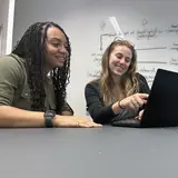 MiChaela Barker at Yale Ventures looking at computer with a colleague pointing to the screen