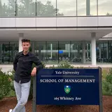 person standing next to the Yale School of Management sign