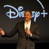 Disney CEO Bob Iger on stage in black suit holding microphone