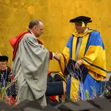 Two men in academic regalia shaking hands