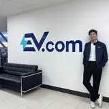 Joel Li next to an EV.com sign