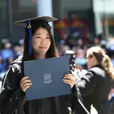 A graduating student holding up a diploma