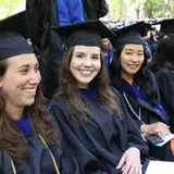 Three seated students wearing caps and gowns