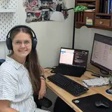 A student wearing headphones and seated in a home office