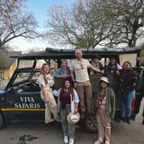 A group of people posing next to a safari vehicle