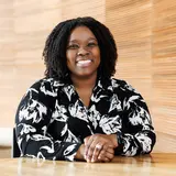 A smiling person photographed against a wood wall