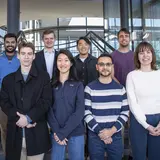 Eight people posing for a photo on a staircase