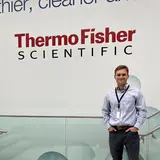 A person standing in front of a wall sign that says “Thermo Fisher Scientific”