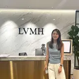 A person standing in an office in front of a wall sign reading “LVMH”