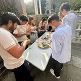 Several people standing around an outdoor table shucking oysters