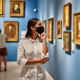 Woman in mask admiring museum artwork