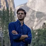 photo of someone with arms crossed standing in a mountain range
